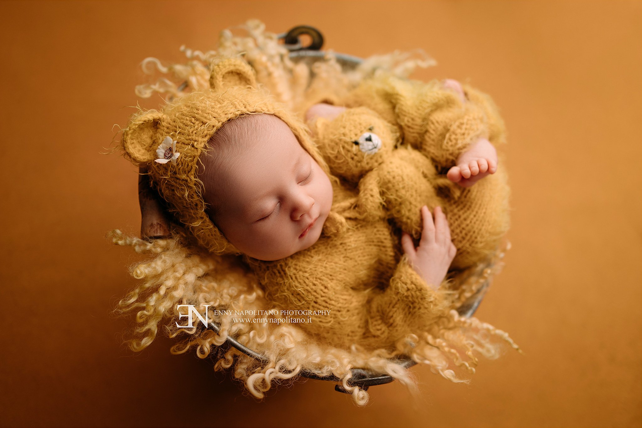 fotografia newborn di una neonata che dorme su un set color giallo