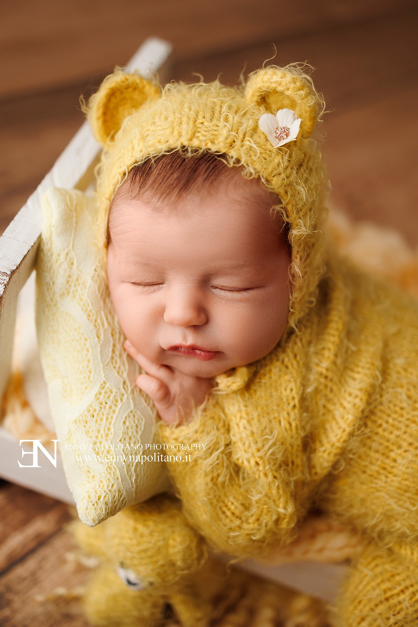 Fotografia newborn di una neonata che dorme su un lettino in un set color giallo