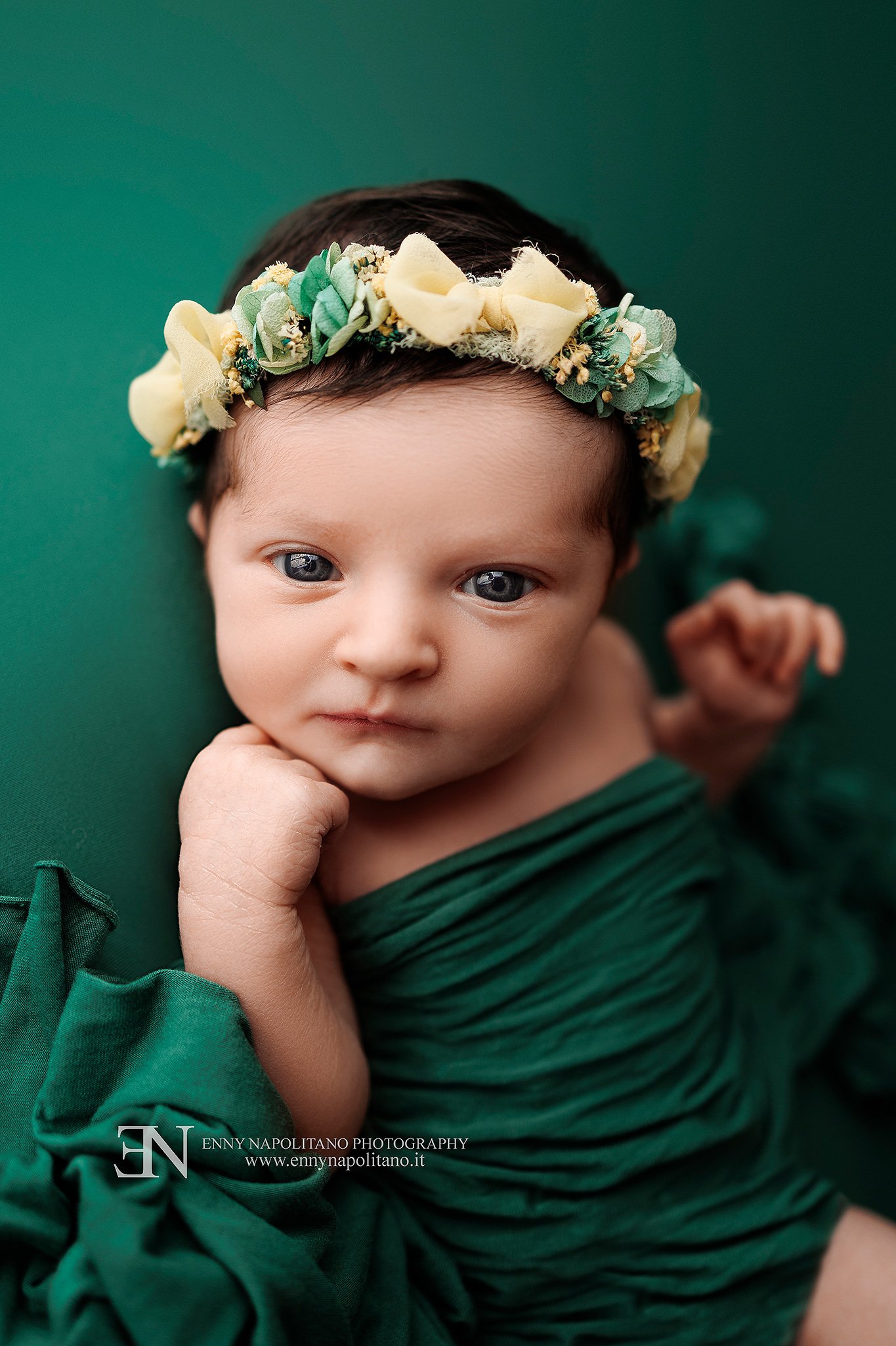Fotografia newborn di una neonata sveglia su un set color verde smeraldo