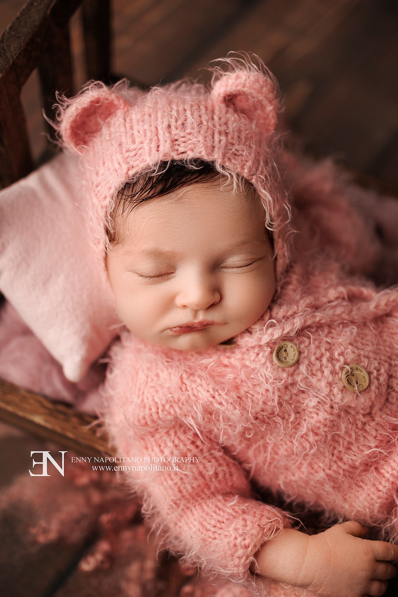 Fotografia newborn di una neonata che dorme su lettino e set colore rosa antico
