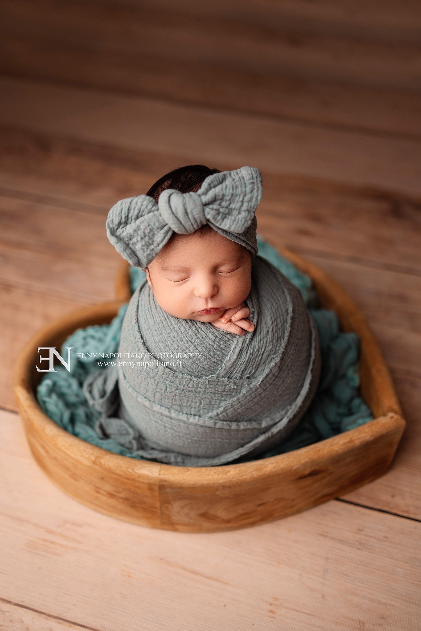 Fotografia newborn di una neonata fasciata all'interno di un prop a forma di cuore