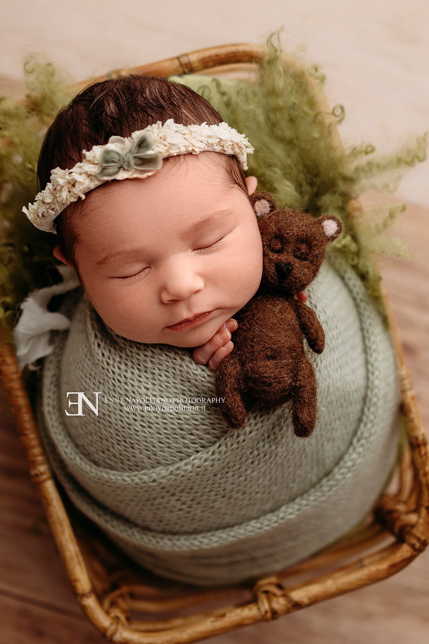 Fotografia newborn di una neonata che dorme fasciata in un set color verde salvia